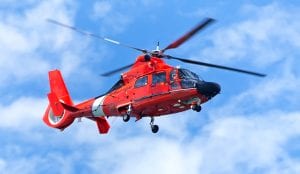 Red rescue helicopter moving in blue sky with blur propeller